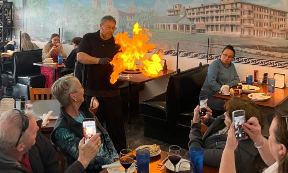 A waiter serving the flaming cheese at the Athena Restaurant