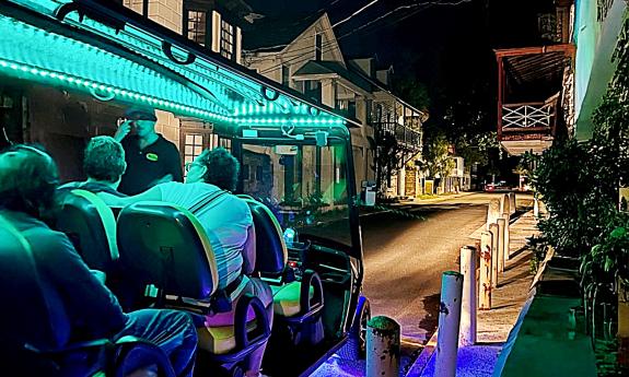 A ghost tour cart lit with green lights on a narrow street in St. Augustine