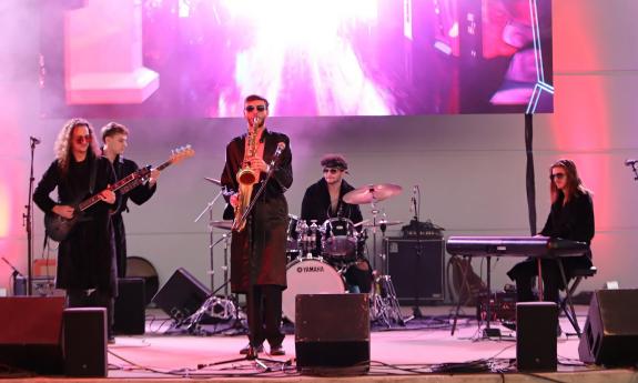 The five-member band, The Fellas, on stage under pink and purple lights