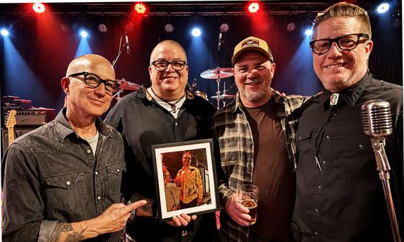 Honest Liars band standing together on stage, behind a mic