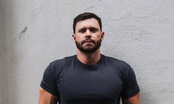 Songwriter Murphy Elmore standing in front of white wall