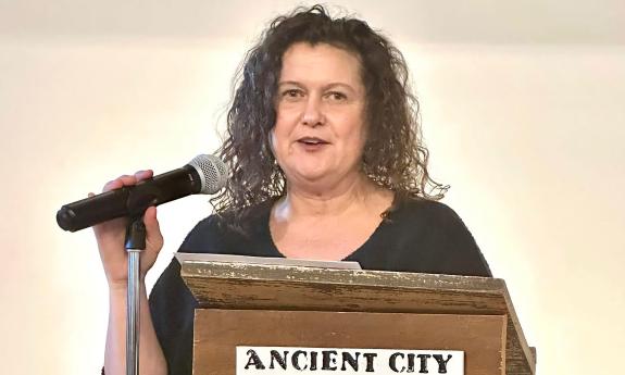 Poet and writer Victoria Nations at a podium presenting her poetry