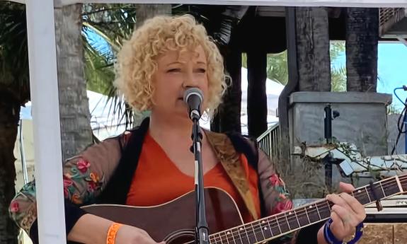 Singer and songwriter Amy Hendrickson performing on an outdoor stage