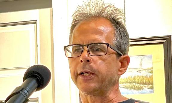 Poet and writer Chris Bodor at a podium presenting his poetry