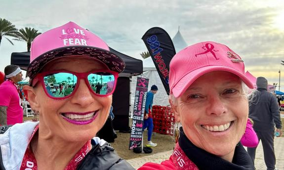 Two women smiling and wearing pink hats having run the DONNA 5K