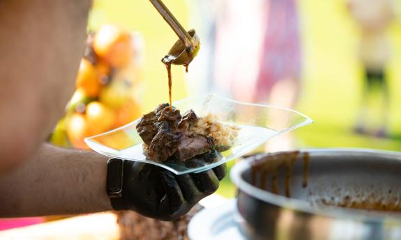 A chef pours gravey over a beef tasting at a food festival