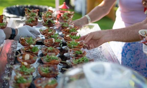 Guests reaching for sample dishes at a food event