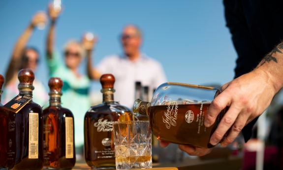 Guests toast in the background as a host pours premium spirits