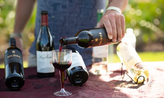 A hosts pours red wine at a tasting held outdoors at Hammock Beach