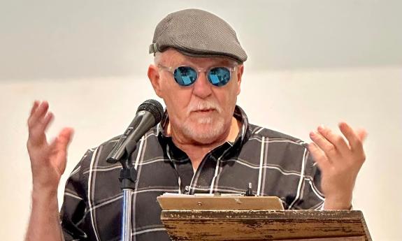 Poet and writer Michael Henry Lee at a podium presenting his poetry
