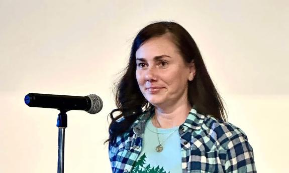 Poet and writer Nicole Zwolinski at a podium presenting her poetry