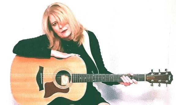 Sparrow Smith (Kathi Witkowski) with her guitar sitting against a white background