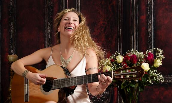 Zaza, guitarist and vocalist performing with passion in an elegant red-velvet room