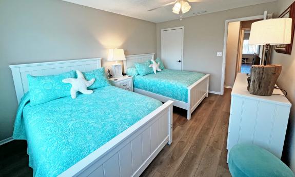 A guest bedroom in a beachside condo features two beds