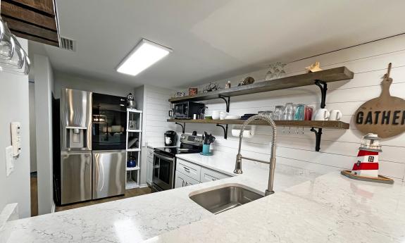 The whtie kitchen in a rental condo has a large fridge and eating counter
