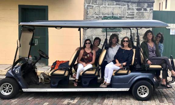Gold Tours with their green large EV, on a St. Augustine Street with clients aboard