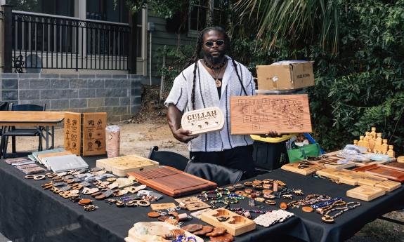 A Gullah Geechee artisan at a table showing his creations