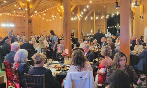 Guests at the Under the Moon Gala sitting at tables for 8 in the decorated Tringali Barn