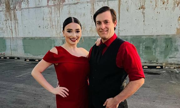 Operatic vocalists Victoria Isernia and John Tibbetts, outside, wearing red and black stage clothing