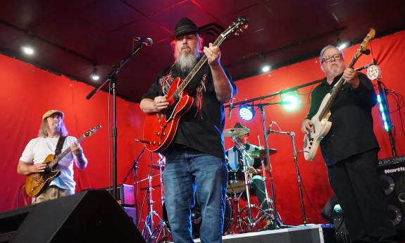 The four members of Mojo Healers performing in a studio against a bright red background