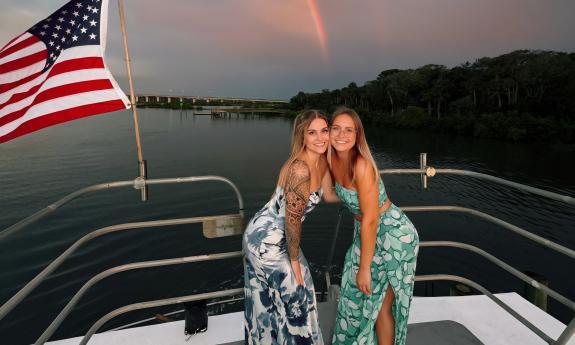 Two women posting at sunset aboard Sea Love II for a party