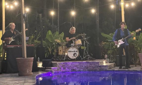 The group Sidewalk 65 performing near a pool