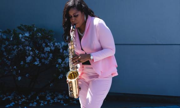 Allana Southerland, wearing a pink suit and playing saxophone