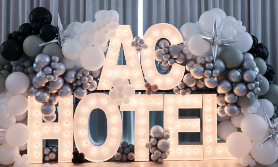 A lighted sign among silver balloons