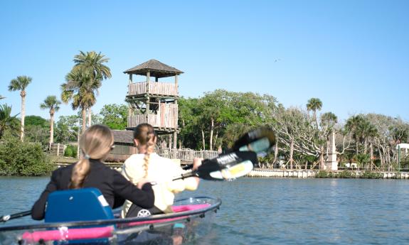 Two young women paddling transparent kayaks near the Fountain of Youth