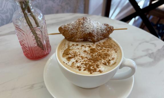 A latte with a small croissant on top