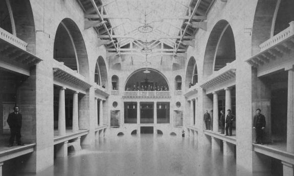 Old photo of Hotel Alcazar pool with men in suits lining the balconys