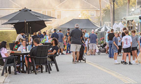 A local festival has seating areas near the food trucks