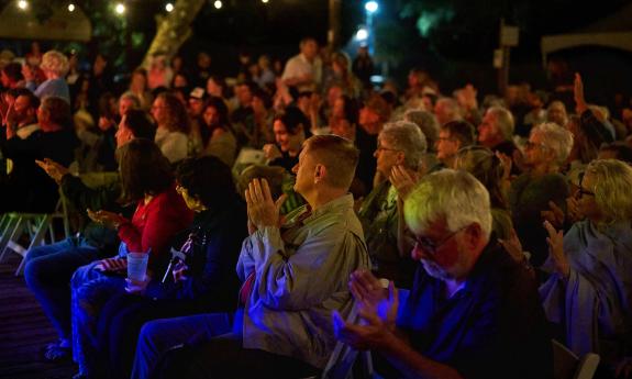 The audience at an outdoor event applauding after a speaker