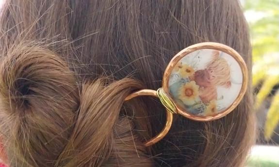 A hand-painted hair clip featuring a long-haired cow
