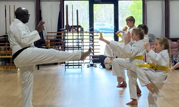 An instructor teaching kids how to kick