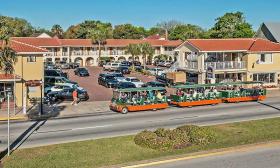 The exterior of the Best Western Bayfront, which has a U-shaped layout facing St. Augustine's Matanzas Bay. A full Old Town trolley tour passes by on Avenida Menendez