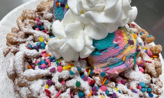 A brightly decorated funnel cake with toppings galore