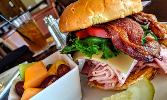 A plated sandwich and a side of fruit