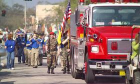 A parade with a band and a firetruck head for the historic downtown