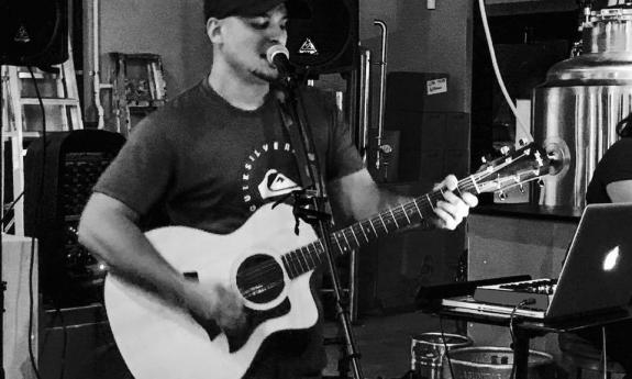 Aaron Mansfield playing his guitar and singing