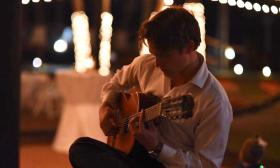 Denis Vasenin playing his guitar at a private event at night.