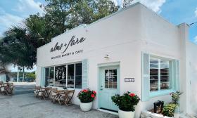 Alms + Fare on San Marco in St. Augustine, presents an inviting entry in a white building with aqua trim.