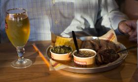 Smoked brisket platter with baked beans, turnip greens, Texas toast, and a glass of beer