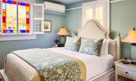 A charming and serene bedroom features a window trimmed in stained glass at the Collector in St. Augustine.