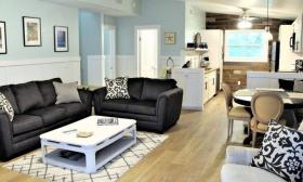 The high-ceiling living room of a home offered by St. Augustine company Florida Rentals is furnished with black and white furniture and beach decorations