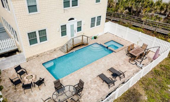  A large yellow-shingled five bedroom house on Anastasia Island. Amongst the dunes, a paver patio with a blue swimming pool and hot tub