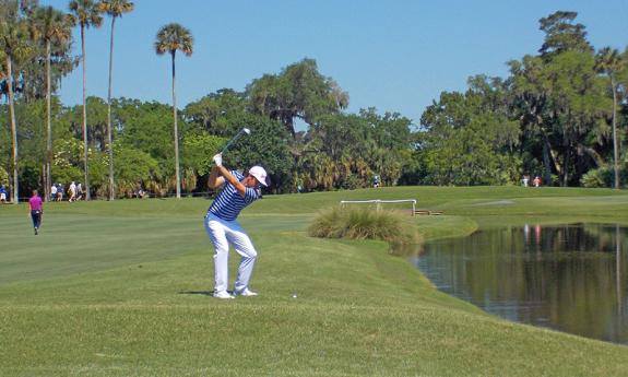 Professional golfers practice their swing on the course during the practice days before the competition.