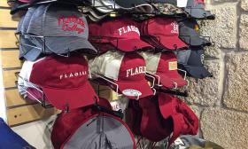 An assortment of hats bearing Flagler College logos and identifiers