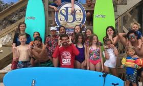 A group of smiling surfers and instructors from Happy Waves Surf Camp in St. Augustine.