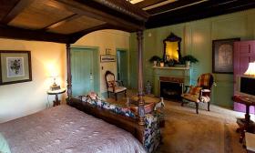 An ornate yet cozy guest room at the Casa de Solana Bed and Breakfast. A king sized canopy bed is surrounded with antique furniture. Across from the bed is a fireplace
